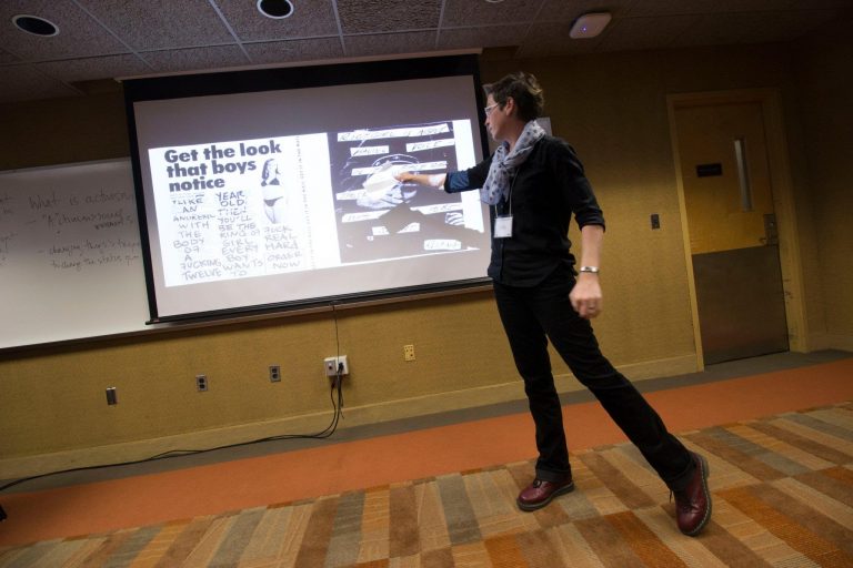 white woman wearing all black gestures at a screen